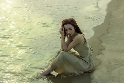 A woman sitting on the beach in a dress