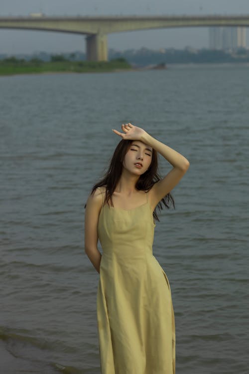 A woman in a yellow dress standing on the shore