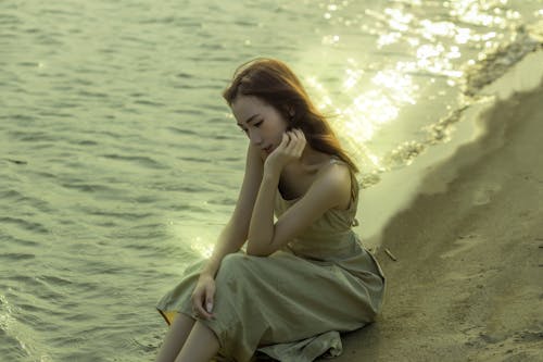 A woman sitting on the beach by the water