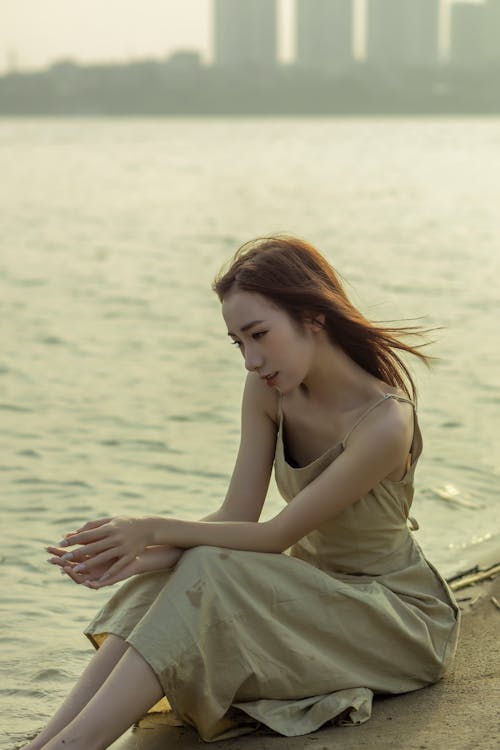 A woman sitting on the ground near water