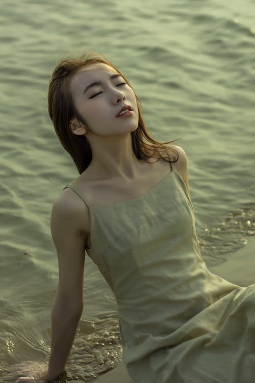 A woman in a dress laying on the beach