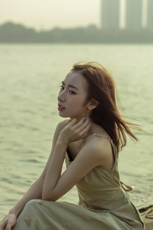 A woman sitting on the ground near water