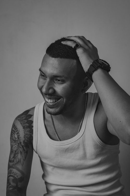 Free Striking black and white portrait of a smiling man with tattoos in a studio setting. Stock Photo