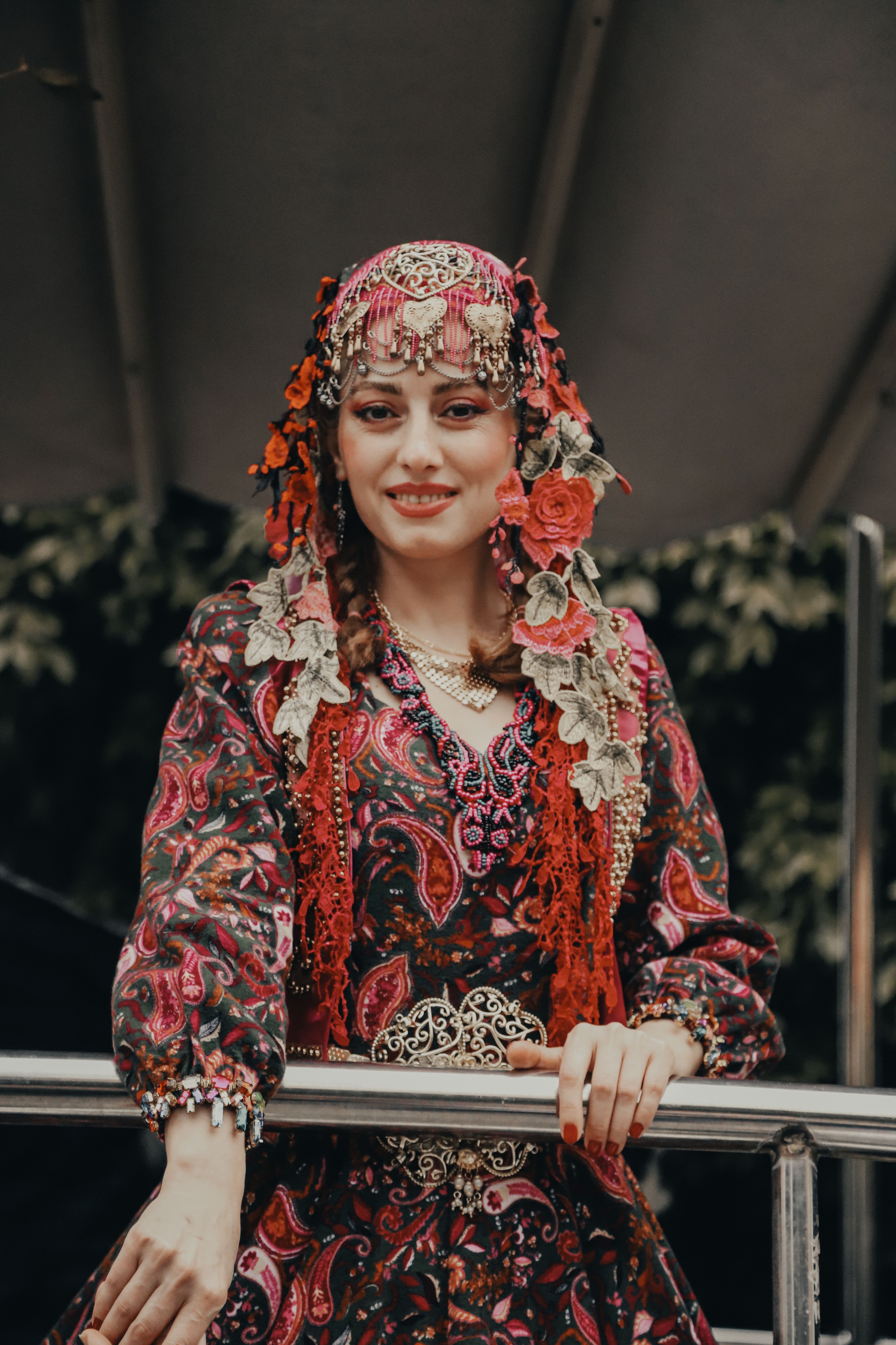A woman in traditional floral costume with ornate headscarf, smiling warmly.