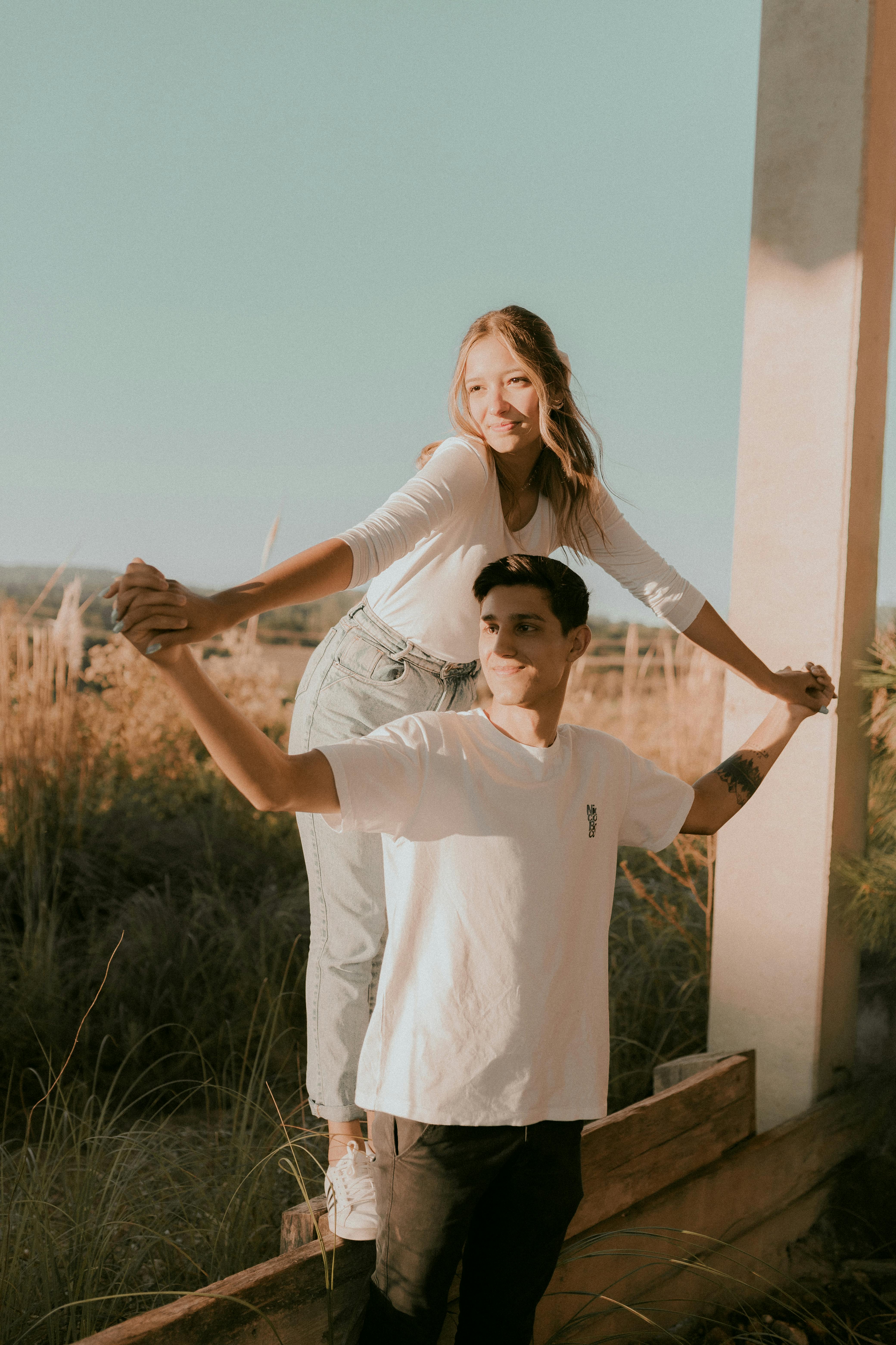 A young couple enjoying a sunny day outdoors, smiling and expressing joy.