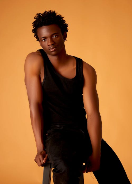 A young black man sitting on a stool