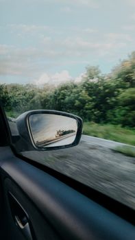 A car mirror reflecting the scenic greenery on a drive through Mossoró, Brazil.