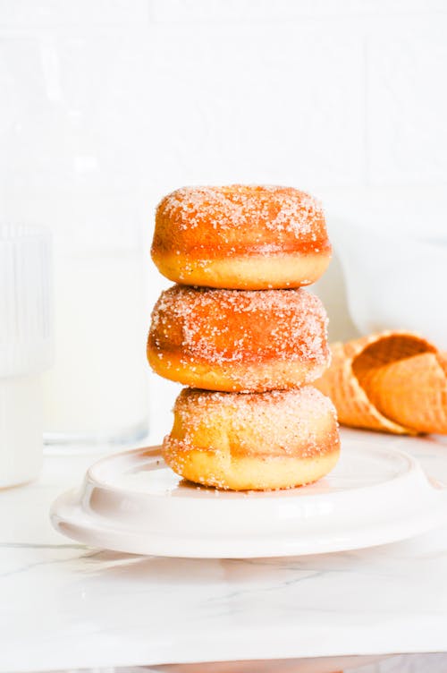 A stack of donuts on a plate with a glass of milk