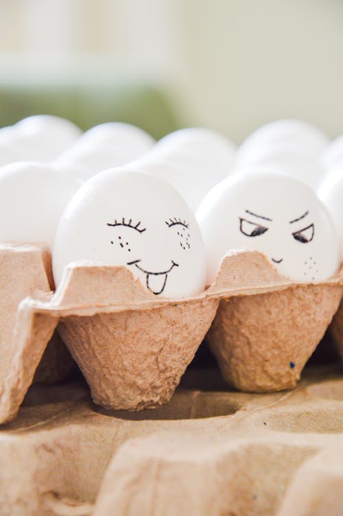 Eggs with faces drawn on them in a carton