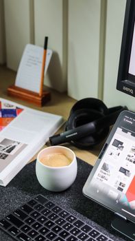 A cozy workspace setup with a cup of coffee, headphones, and digital devices on a desk.