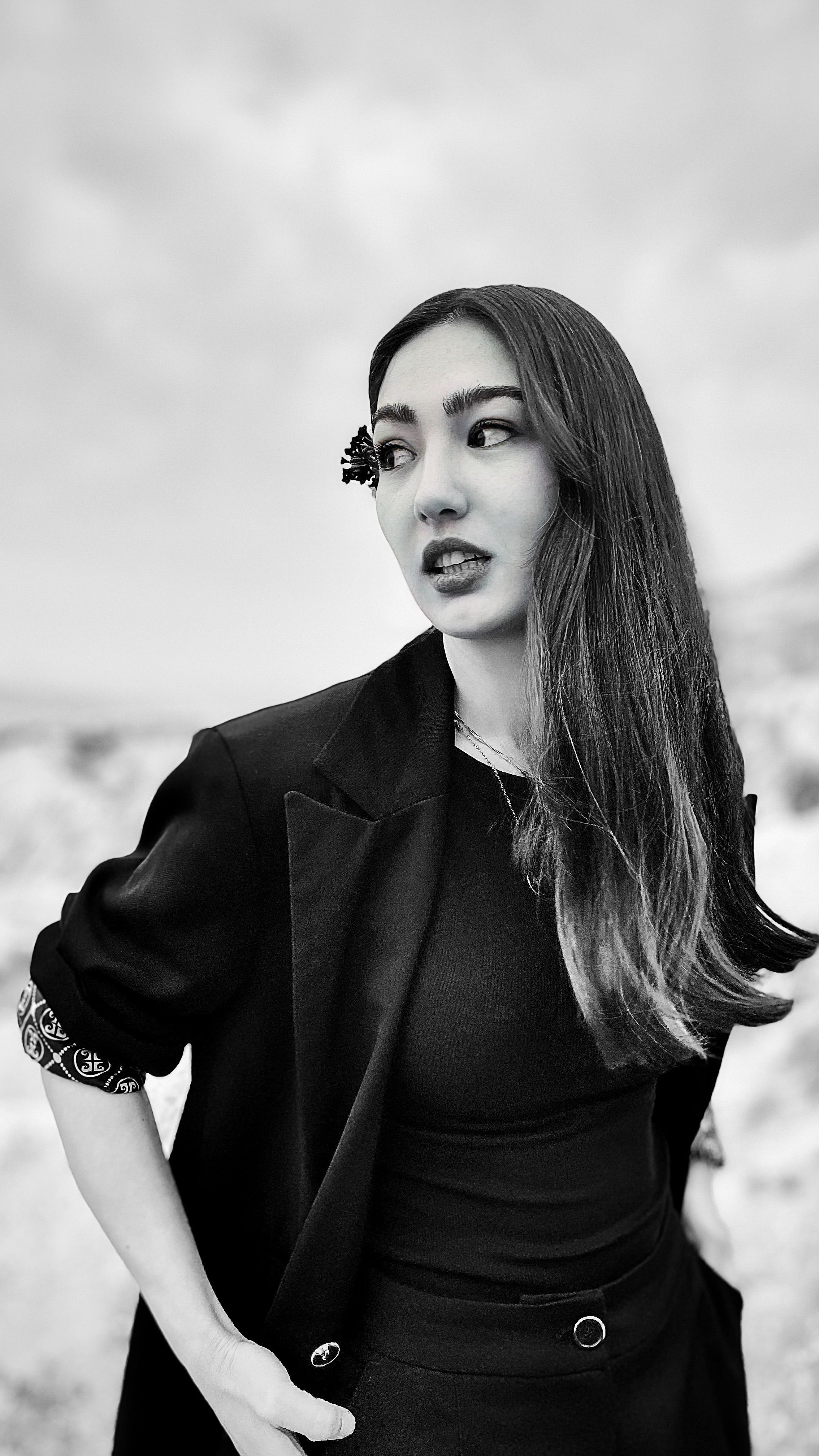 Elegant black and white portrait of a woman with long hair in a suit jacket, embodying modern fashion.