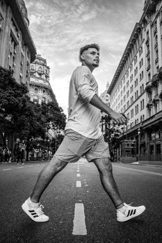 Black and white image of a man confidently walking through urban city streets.