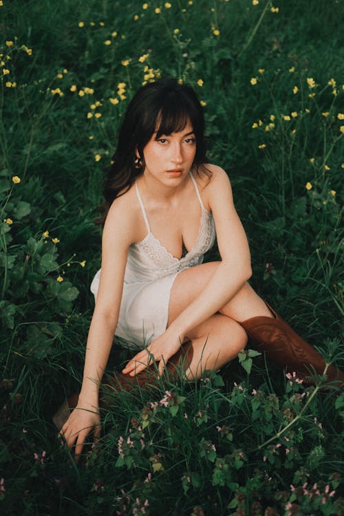 A woman in a white dress sitting in a field
