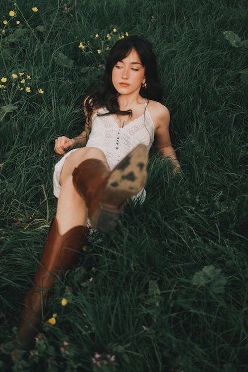 A woman laying in the grass wearing boots