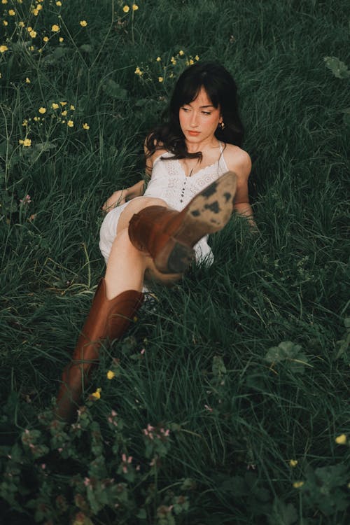 A woman laying down in the grass wearing brown boots