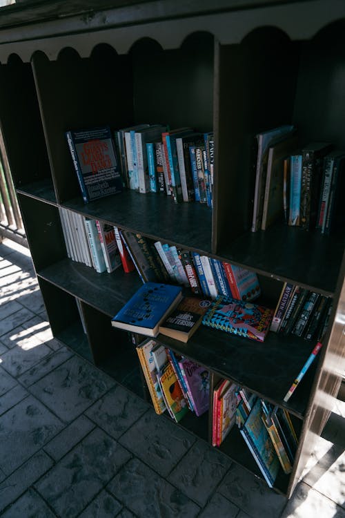 A book shelf with books on it sitting on a porch