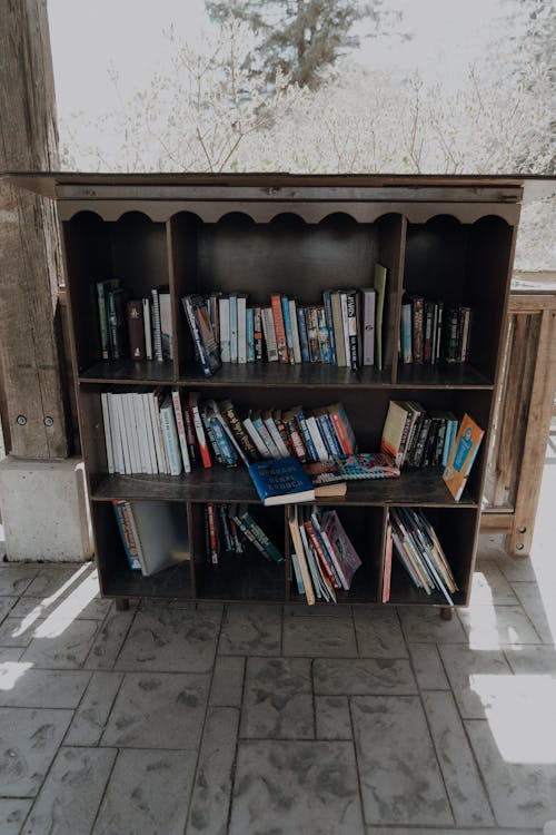 A bookcase with books on it sitting on a porch