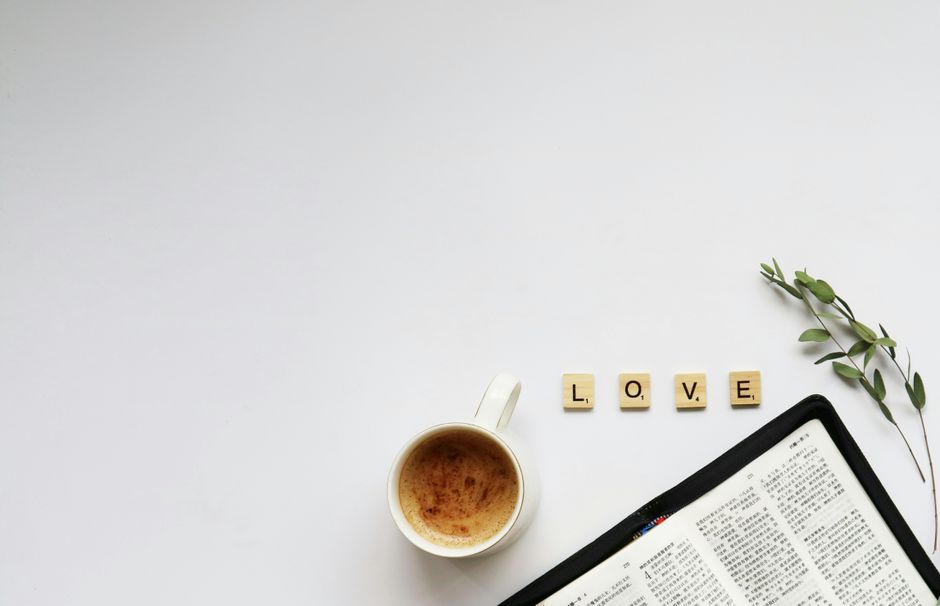 Top view of a coffee cup, love tiles, and an open book on a white background.