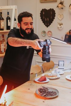 Photographer using DSLR in São Paulo café capturing desserts and coffee setup.