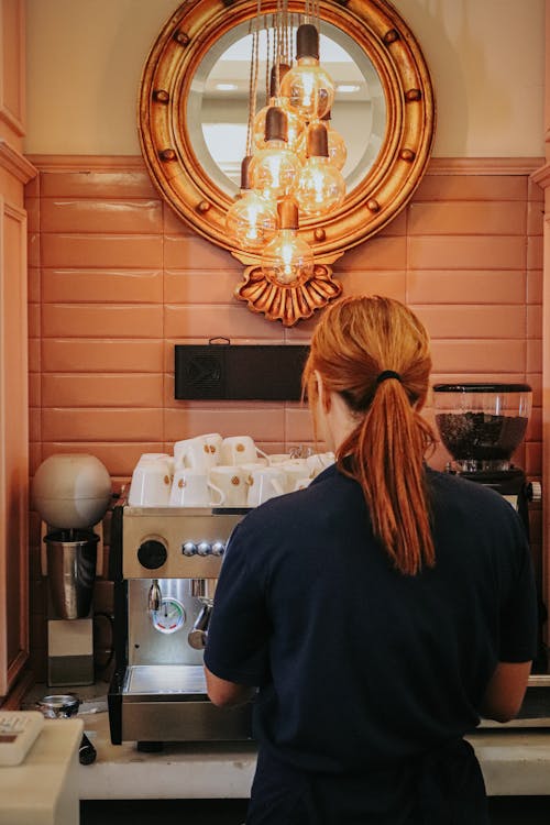 A woman is standing in front of a coffee machine