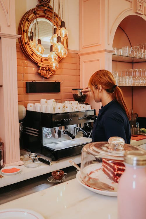 A woman is making coffee in a pink cafe