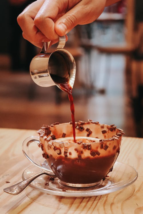 A person pouring coffee into a cup with chocolate