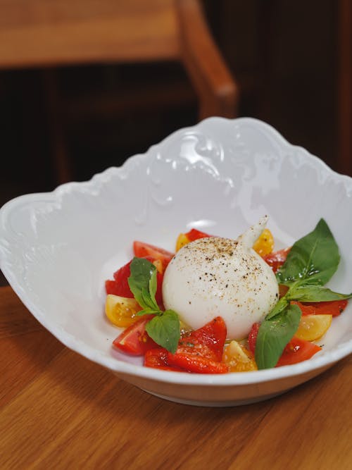 A white bowl filled with tomatoes, basil and mozzarella
