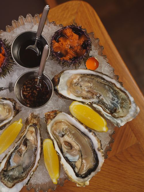 Free Delicious oyster platter with lemons, ice, and sauces for a gourmet dining experience. Stock Photo