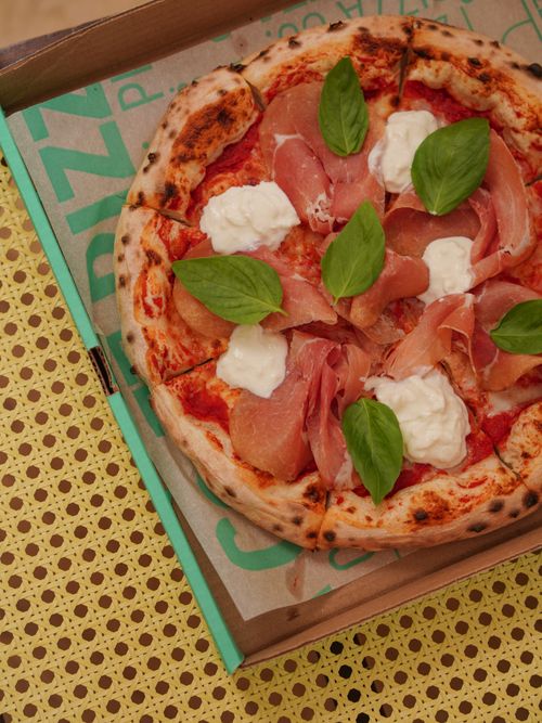 Free Savor this fresh prosciutto pizza topped with basil and cream cheese, perfect for a gourmet meal. Stock Photo