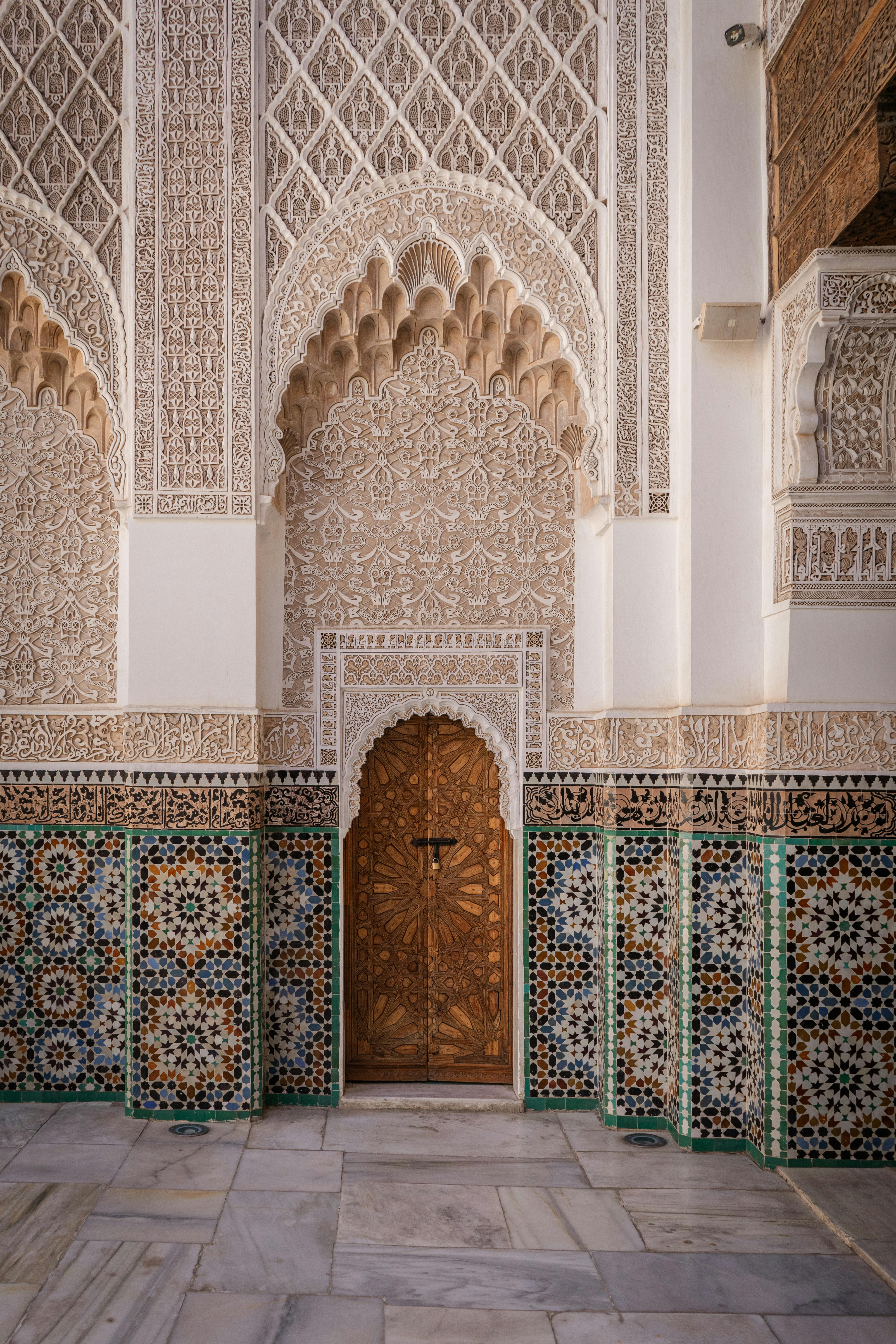 Explore the stunning detailed Moorish architecture with mosaic tiles at the entrance of a historic building in Marrakesh, Morocco.