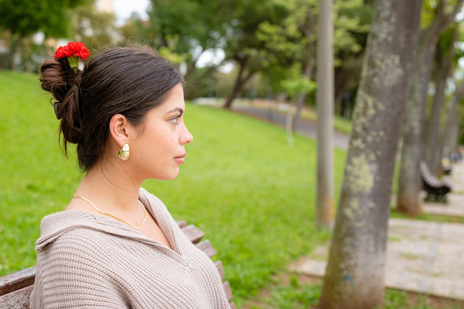 Young woman sitting in a park, enjoying nature with a red flower in hair
