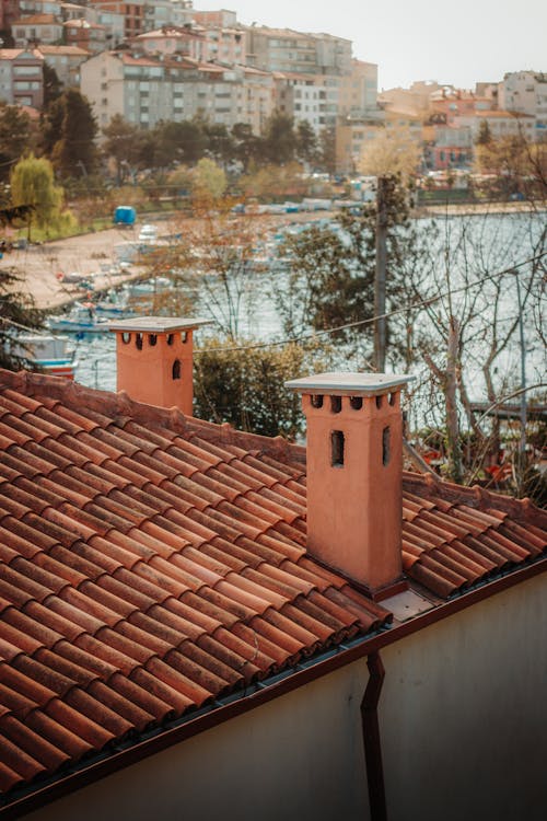 A view of a roof with red tiles and a city in the background