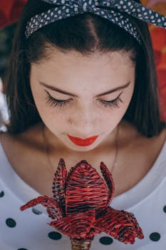 一名戴着圆点头带的女子低头看着一朵红花的特写肖像