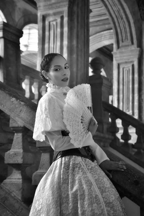 A woman in a dress and fan on a staircase