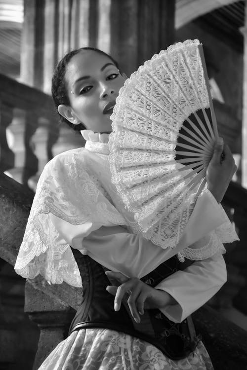 A woman in a dress holding a fan