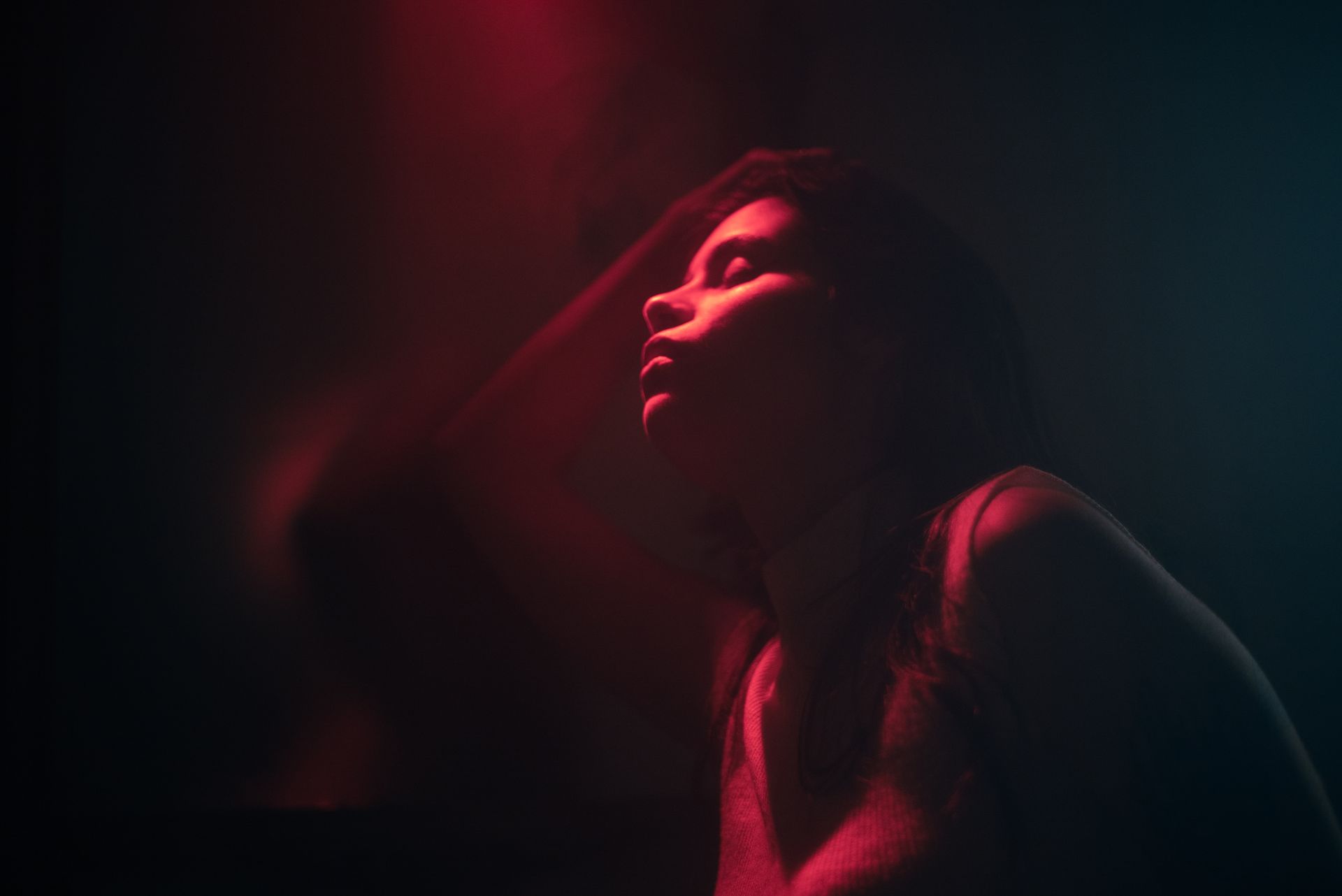 Artistic portrait of a woman with dramatic red lighting and shadows.