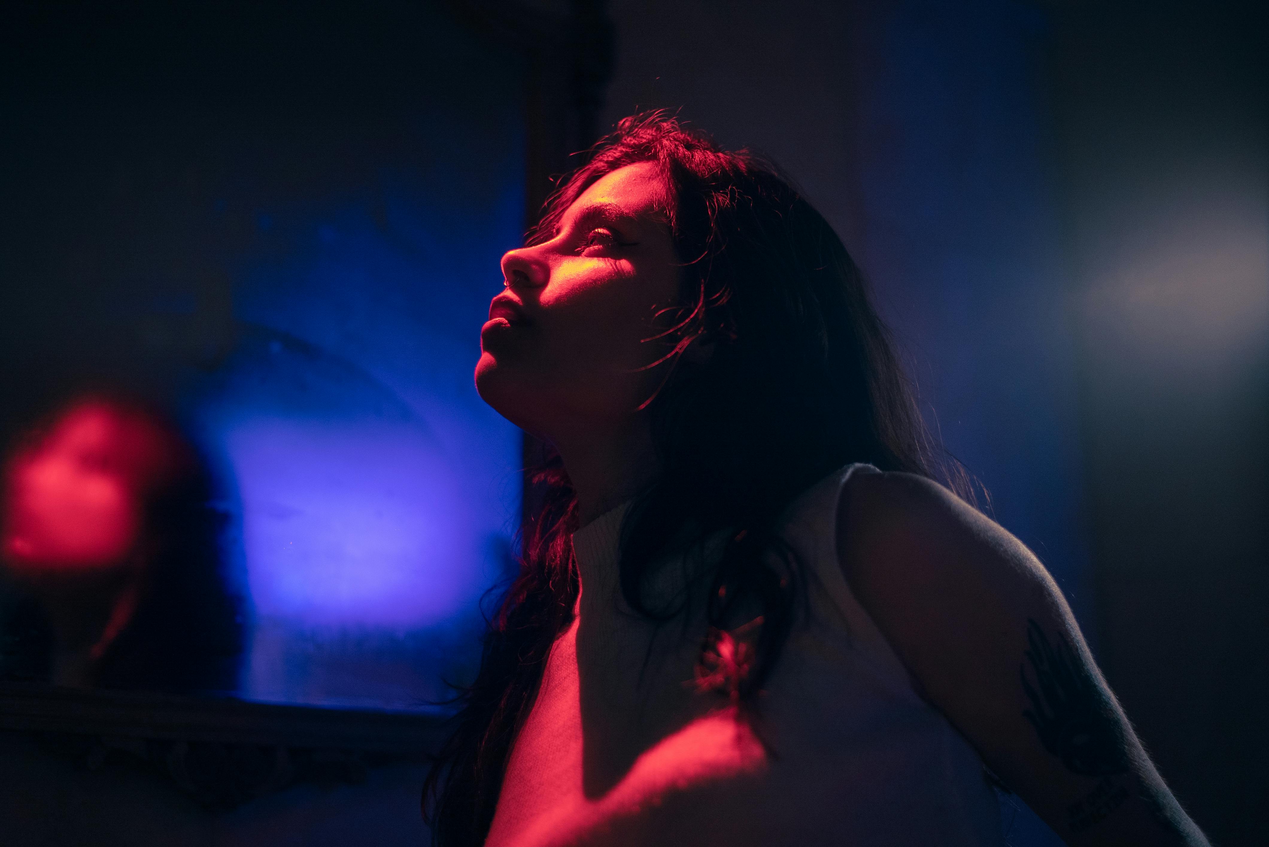 Artistic portrait of a woman in dramatic red and blue lighting, creating a moody atmosphere.