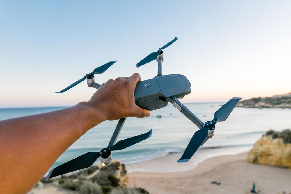 Drone lifting off over a beach celebration at golden hour