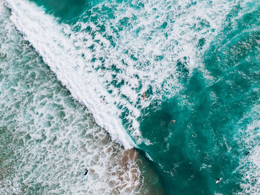 Aerial shot of surfers riding waves in Albufeira, Portugal's turquoise ocean. Perfect summer adventure.