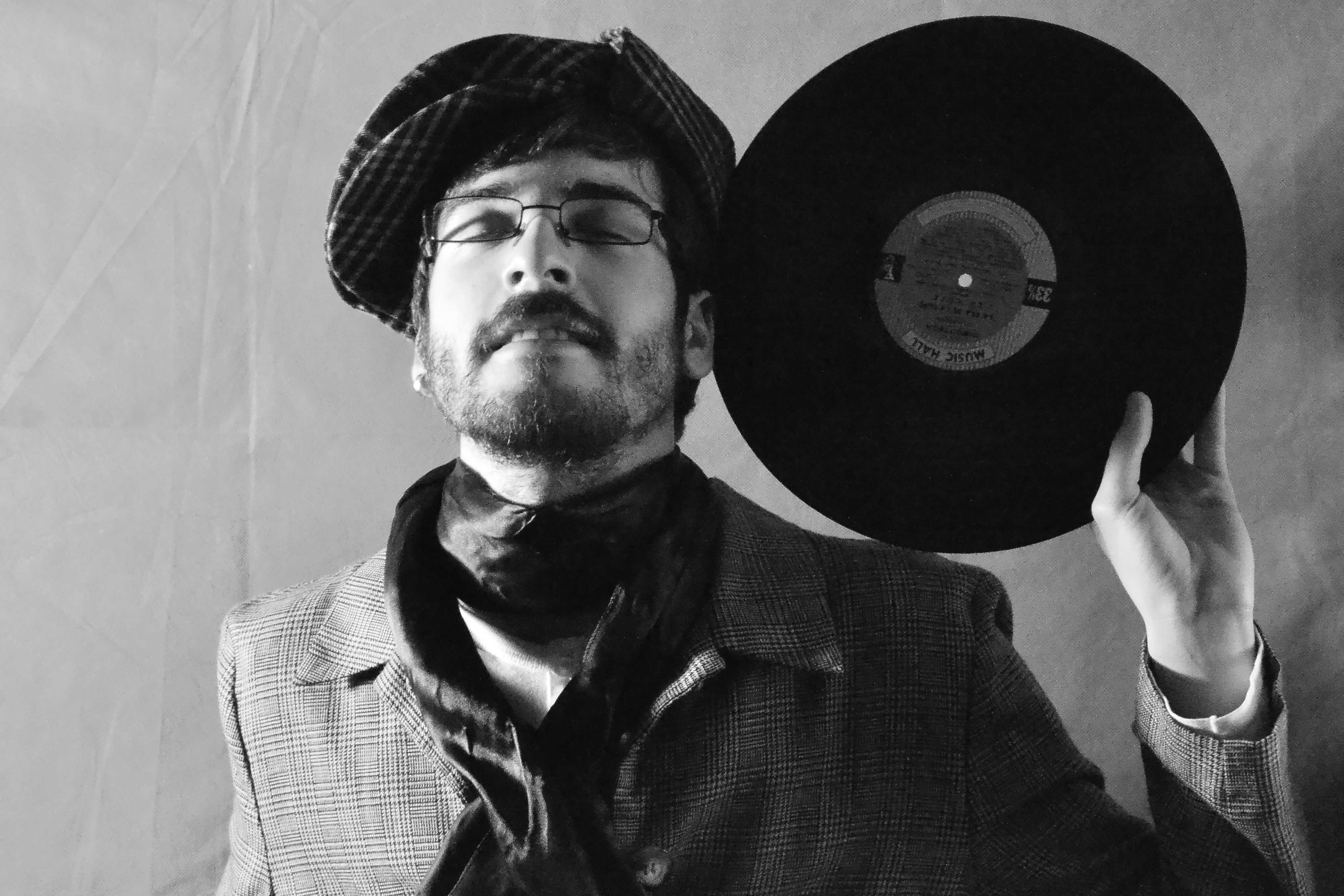 Vintage-styled portrait of a man with a vinyl, showcasing elegance and retro fashion.