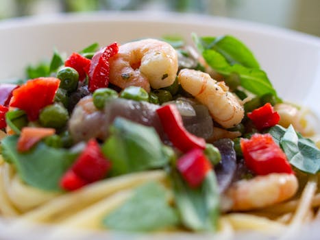 Delicious shrimp pasta garnished with fresh vegetables and herbs, perfect for a healthy meal.
