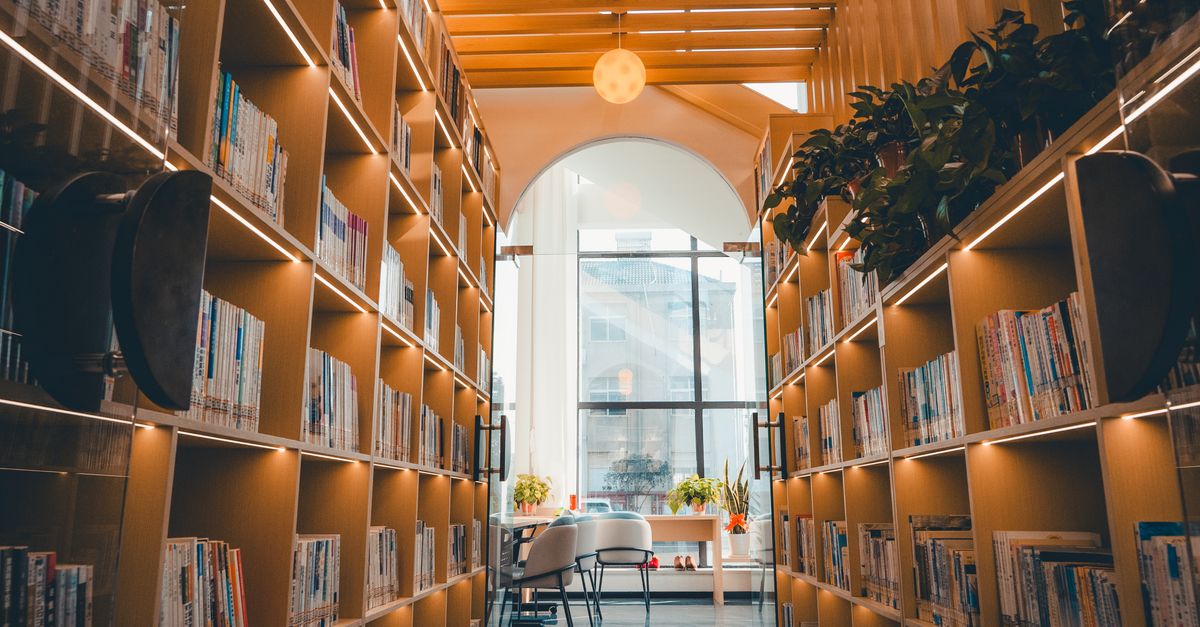 Library. Photos Library Interior and Wooden Illuminated Bookshelves · Free Stock Photo