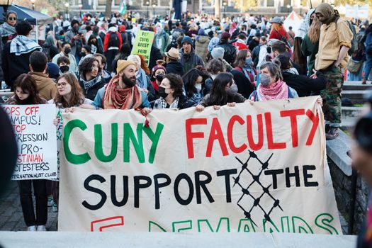 Crowd gathers for CUNY faculty support protest with signs and banners advocating demands.