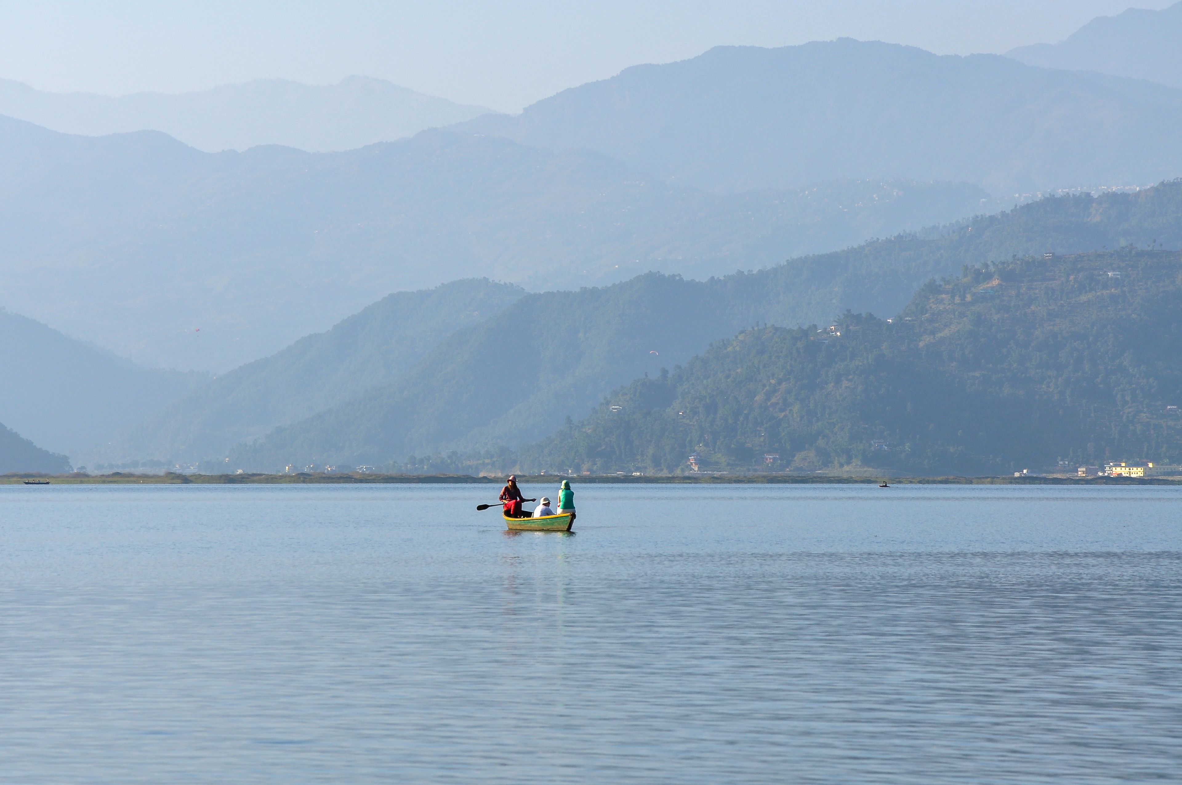 Kayakers on Phewa Lake beneath misty hills