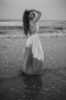 Black and white portrait of a woman in a dress by the seaside.