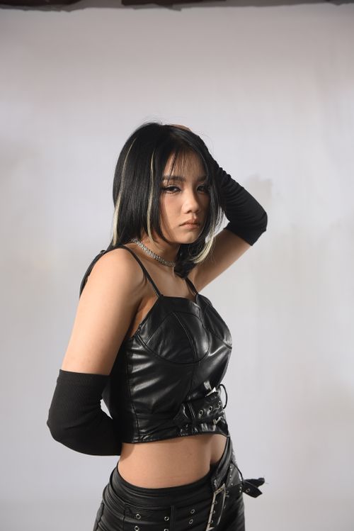 Free Portrait of a young woman posing in a black leather outfit in a studio setting. Stock Photo