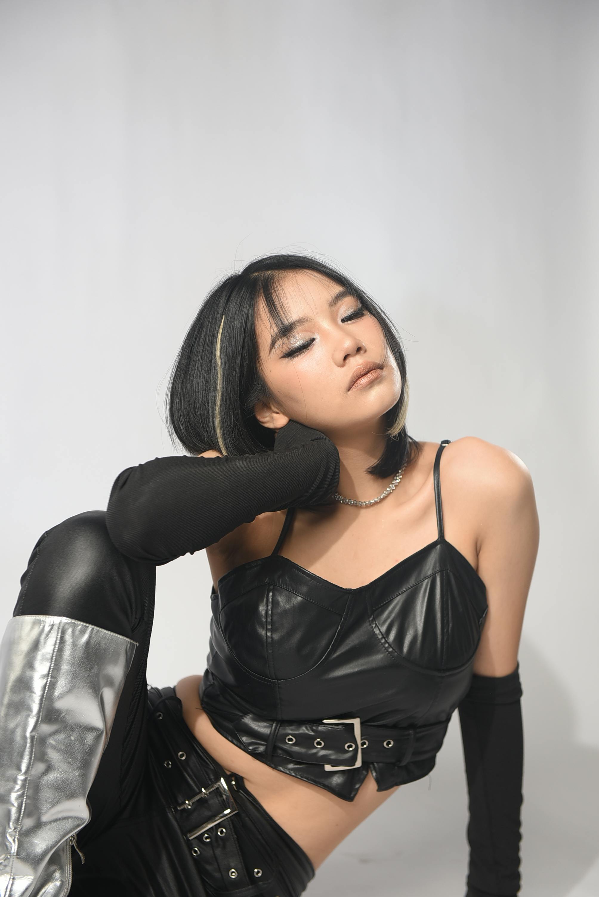 studio shoot of a model wearing a black leather outfit and silver boots