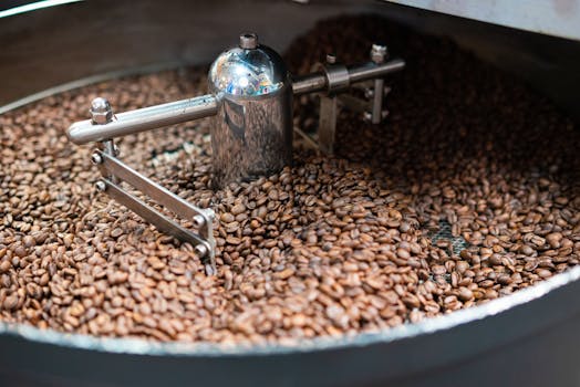 Close-up of coffee beans being roasted in a metal roaster, highlighting freshness.