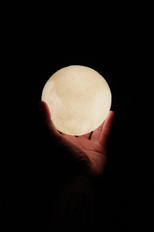 A person holding a full moon in their hand