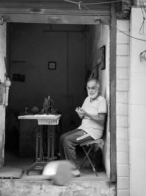 A man sitting in a doorway with a sewing machine